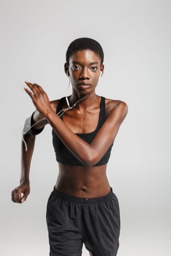 Image of african american sportswoman using cellphone and earphones